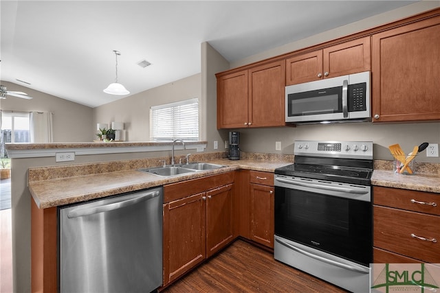 kitchen featuring sink, dark wood-type flooring, decorative light fixtures, vaulted ceiling, and appliances with stainless steel finishes