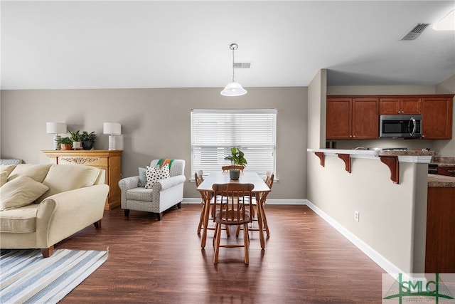 dining space with dark wood-type flooring and vaulted ceiling