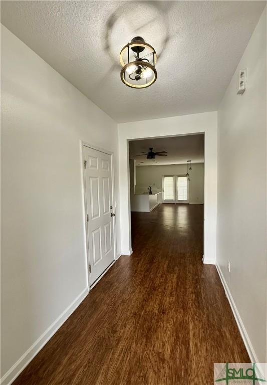 hall featuring a textured ceiling and dark hardwood / wood-style flooring