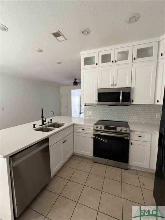 kitchen with kitchen peninsula, appliances with stainless steel finishes, sink, and white cabinetry