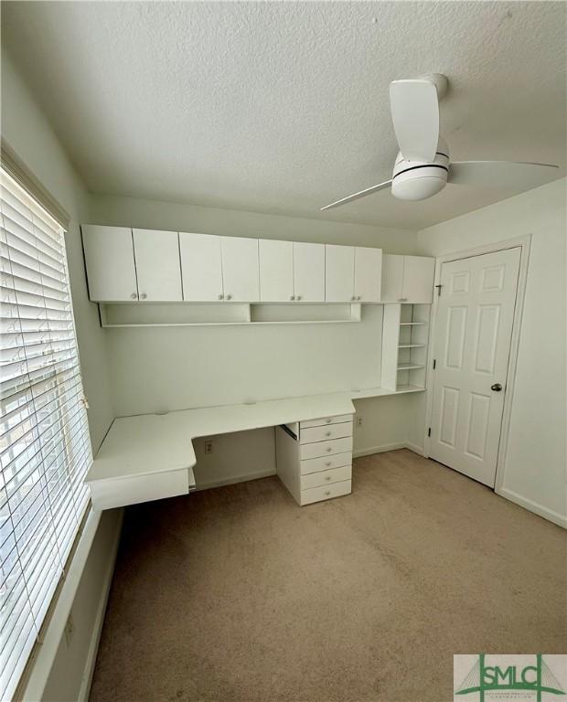 unfurnished office with ceiling fan, a textured ceiling, and light carpet