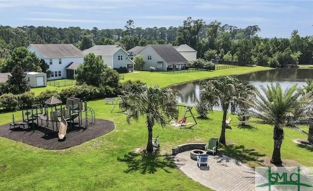 view of home's community featuring a playground, a yard, a water view, and a fire pit