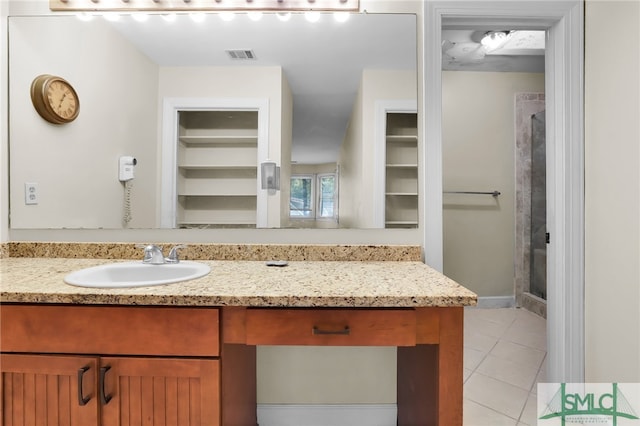 bathroom with a shower, tile patterned flooring, and vanity