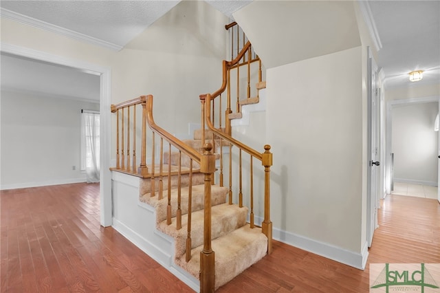 staircase with hardwood / wood-style flooring, crown molding, and a textured ceiling