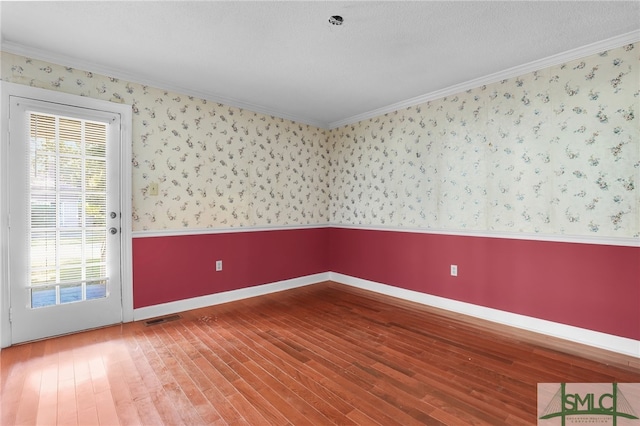 spare room with hardwood / wood-style floors, a textured ceiling, and crown molding