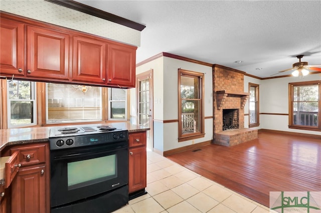 kitchen featuring a wealth of natural light, light wood-type flooring, a textured ceiling, and black range with electric cooktop