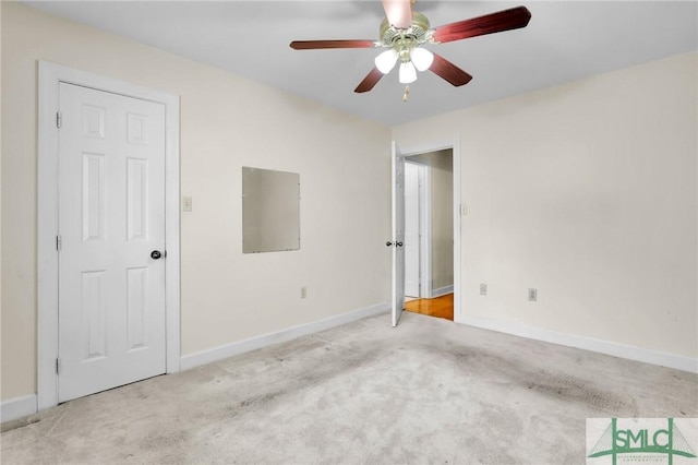 carpeted spare room featuring baseboards and a ceiling fan