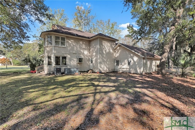 rear view of property with central AC and a lawn