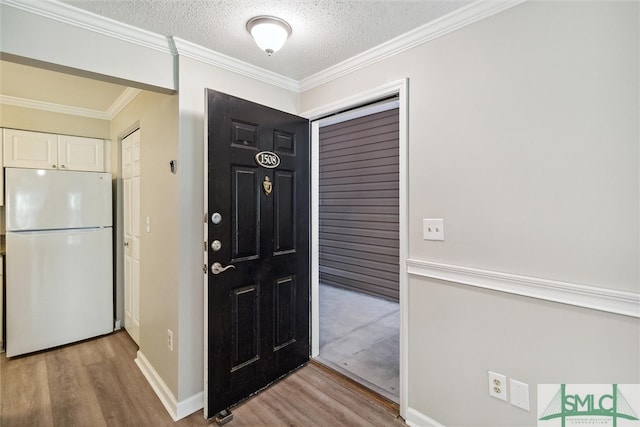 foyer with a textured ceiling, light hardwood / wood-style floors, and crown molding