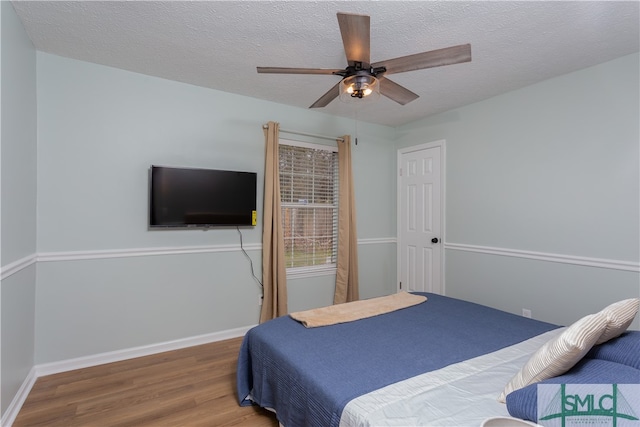 bedroom with hardwood / wood-style floors, ceiling fan, and a textured ceiling