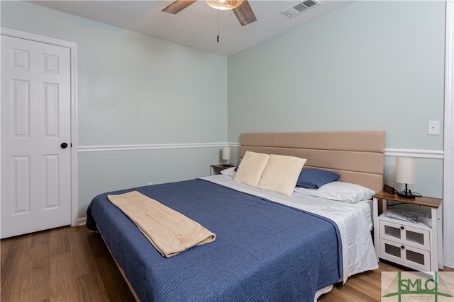 bedroom featuring hardwood / wood-style flooring, ceiling fan, and a textured ceiling