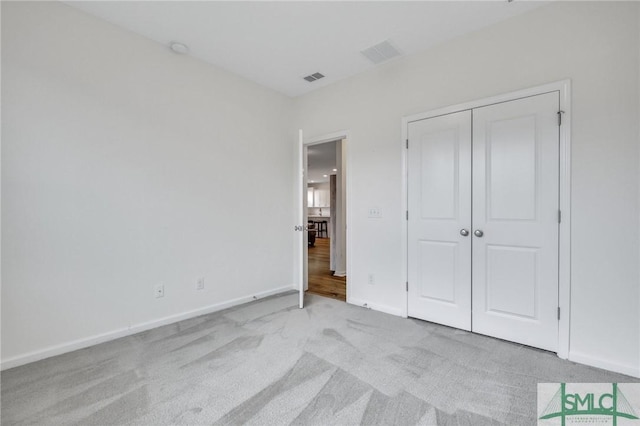 unfurnished bedroom featuring light carpet and a closet