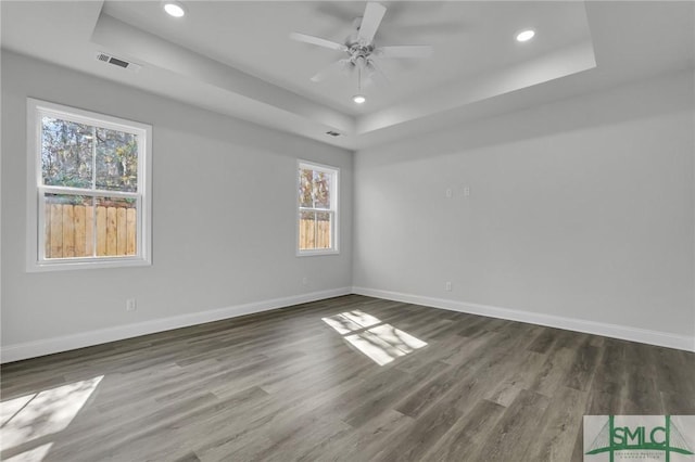 unfurnished room featuring ceiling fan, dark hardwood / wood-style floors, and a raised ceiling