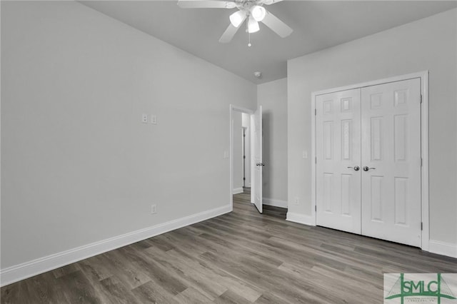 unfurnished bedroom featuring hardwood / wood-style floors, a closet, and ceiling fan