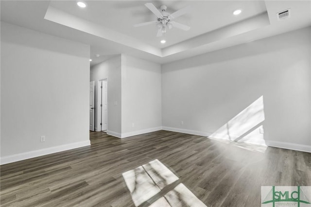 unfurnished room featuring dark hardwood / wood-style flooring, a raised ceiling, and ceiling fan