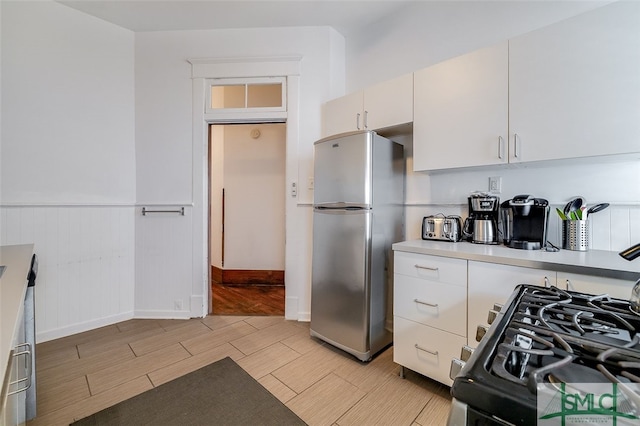 kitchen featuring stainless steel fridge, white cabinetry, and range