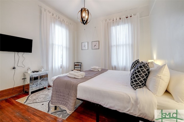 bedroom with multiple windows, wood-type flooring, and an inviting chandelier