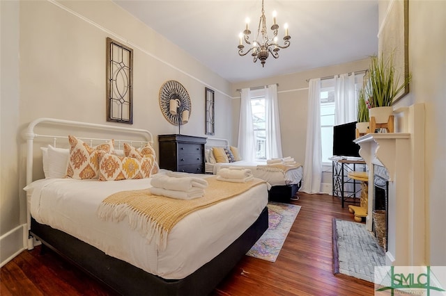 bedroom with a fireplace, dark wood-type flooring, and a chandelier