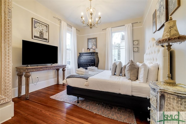 bedroom with dark hardwood / wood-style floors and an inviting chandelier