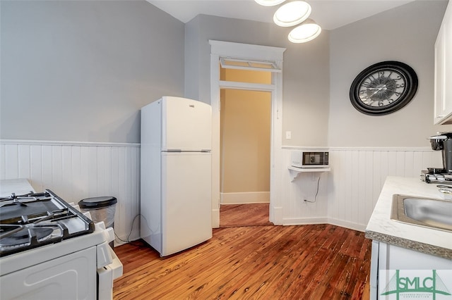 kitchen with white cabinets, white appliances, light hardwood / wood-style flooring, and sink