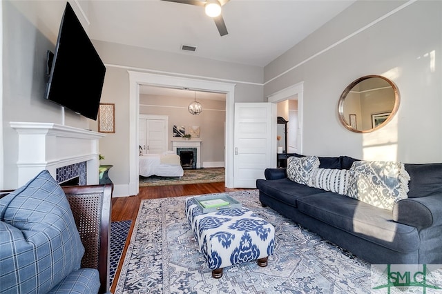 living room with ceiling fan with notable chandelier and wood-type flooring