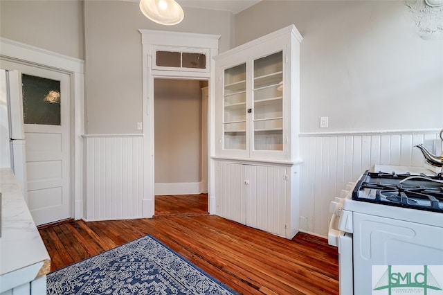 kitchen with white cabinets, white gas range oven, and dark wood-type flooring