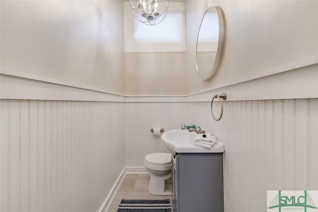 bathroom with a notable chandelier, vanity, toilet, and wood-type flooring