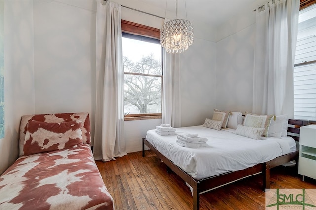 bedroom featuring hardwood / wood-style floors, a notable chandelier, and multiple windows