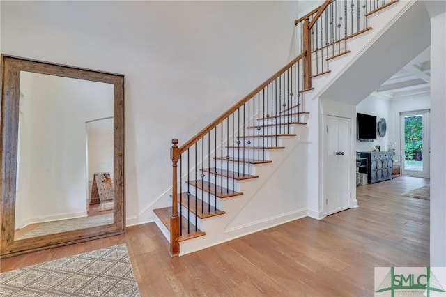 staircase with hardwood / wood-style flooring and beamed ceiling