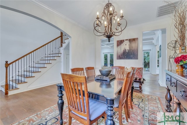 dining room featuring beam ceiling, french doors, crown molding, hardwood / wood-style floors, and a chandelier