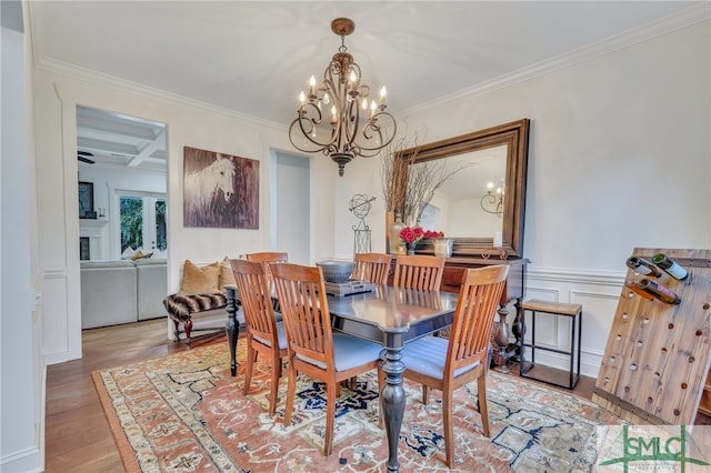 dining area featuring ornamental molding, coffered ceiling, beam ceiling, an inviting chandelier, and hardwood / wood-style floors