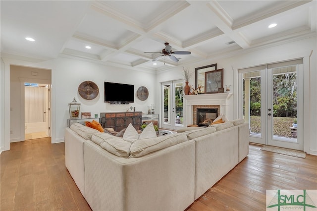 living room with ceiling fan, light hardwood / wood-style floors, beam ceiling, and french doors