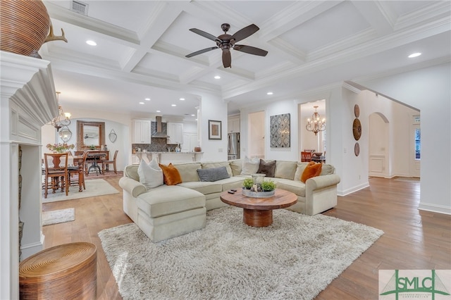 living room featuring beam ceiling, coffered ceiling, light hardwood / wood-style floors, and ceiling fan with notable chandelier