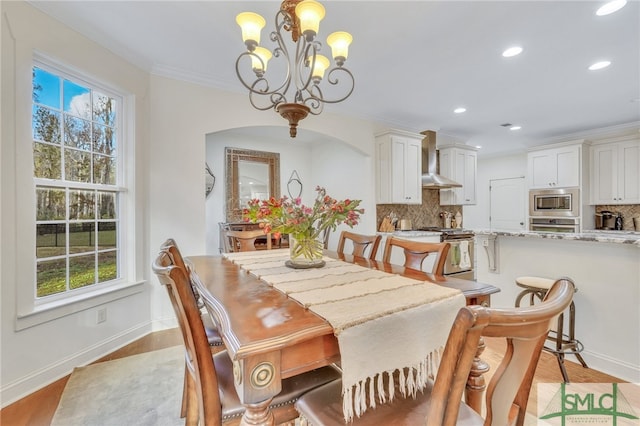 dining room with light hardwood / wood-style flooring, a notable chandelier, and crown molding