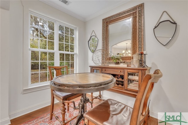 sitting room featuring wood-type flooring, crown molding, a wealth of natural light, and a notable chandelier