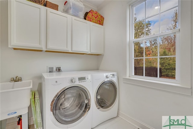 washroom with cabinets, sink, a wealth of natural light, and washing machine and clothes dryer