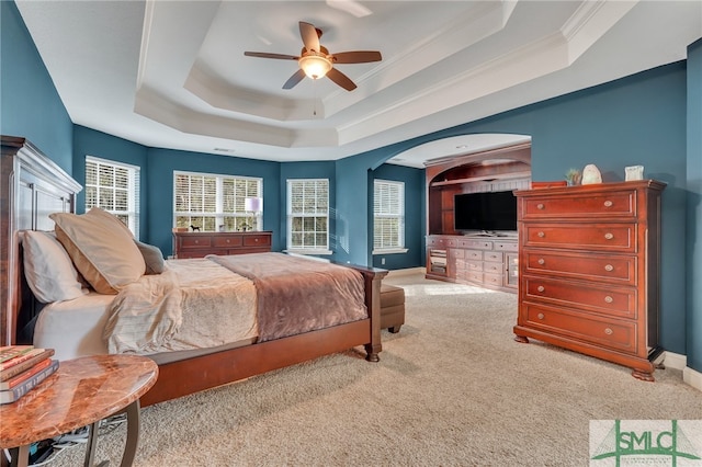 bedroom with light carpet, a raised ceiling, ceiling fan, and ornamental molding