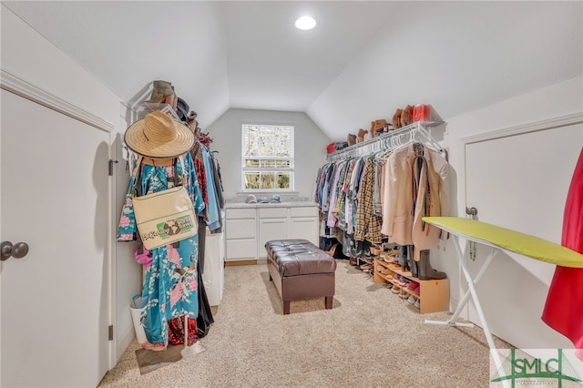 walk in closet with light colored carpet and lofted ceiling