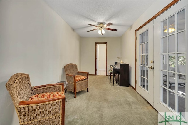 living area featuring ceiling fan, french doors, light carpet, and a textured ceiling