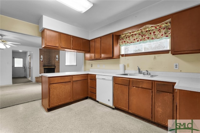 kitchen featuring kitchen peninsula, a brick fireplace, white dishwasher, ceiling fan, and sink