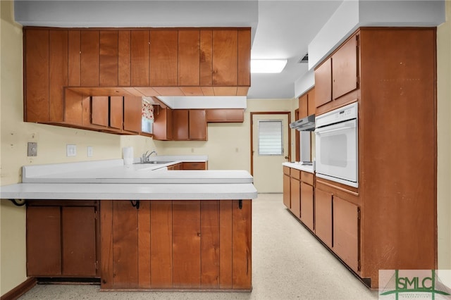 kitchen featuring kitchen peninsula, sink, and white oven