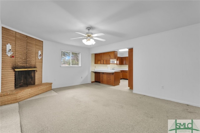 unfurnished living room featuring sink, ceiling fan, light colored carpet, and a fireplace