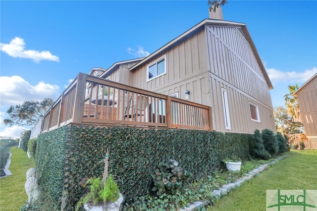 back of house featuring a lawn and a wooden deck