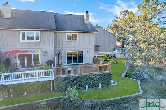 rear view of house with a lawn and a wooden deck