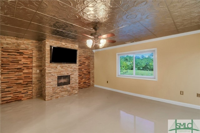 unfurnished living room featuring ceiling fan, a stone fireplace, and ornamental molding