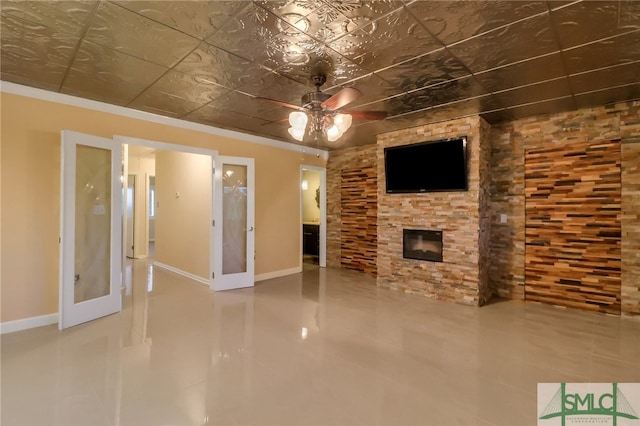 unfurnished living room with ceiling fan, a fireplace, crown molding, and french doors