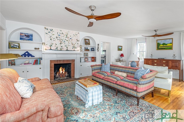 living room featuring ceiling fan, a fireplace, and hardwood / wood-style flooring