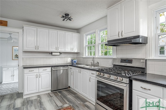 kitchen featuring a wealth of natural light, sink, white cabinets, and appliances with stainless steel finishes