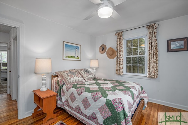 bedroom with multiple windows, hardwood / wood-style flooring, and ceiling fan