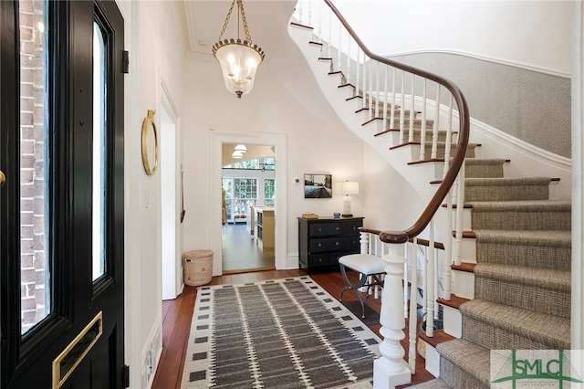 foyer with a chandelier, dark hardwood / wood-style floors, and ornamental molding